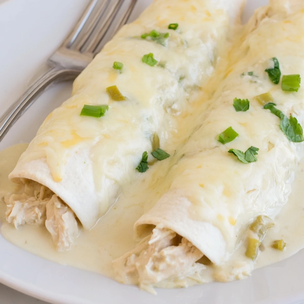Baked Creamy White Chicken Enchiladas in casserole dish, golden edges, tempting cheese pull