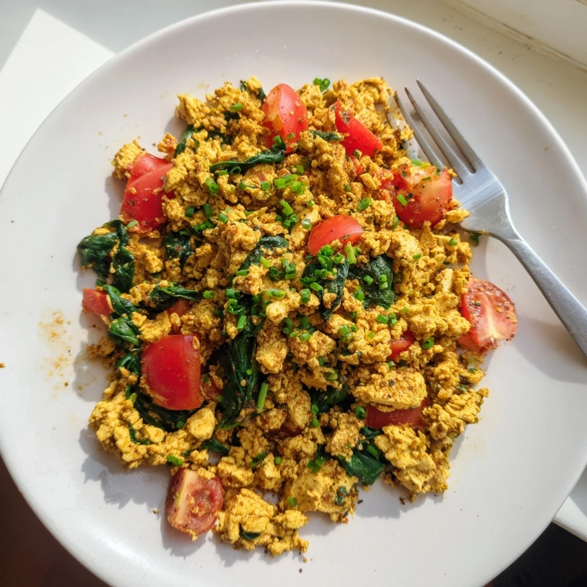 Bright Tofu Scramble piled on toast with creamy avocado and chives
