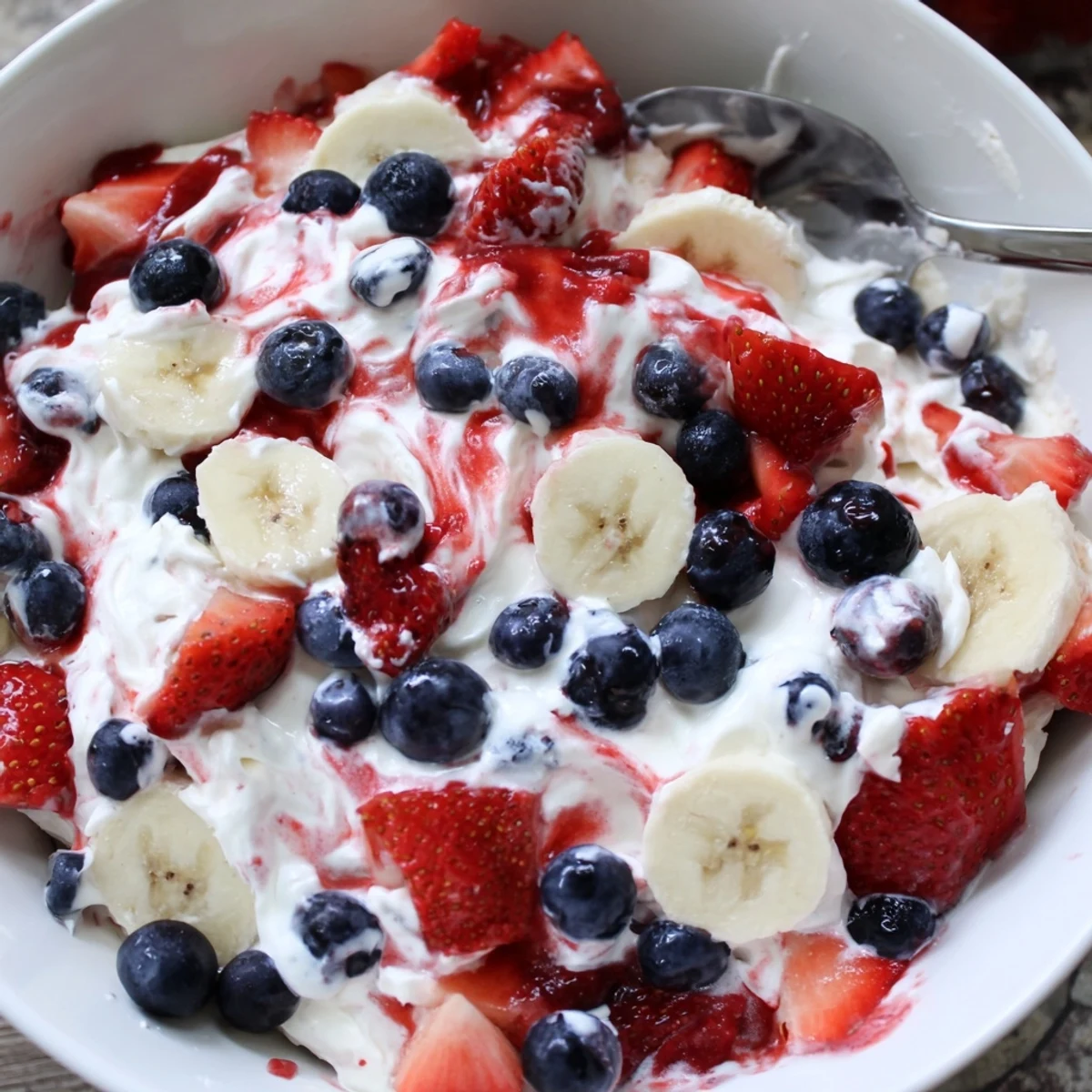 Spoonful of Red White And Blue Cheesecake Salad showing fluffy, tangy fruit filling