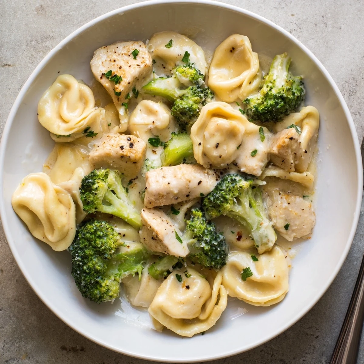 Creamy Garlic Parmesan Tortellini Chicken Broccoli Recipe served hot with grated Parmesan