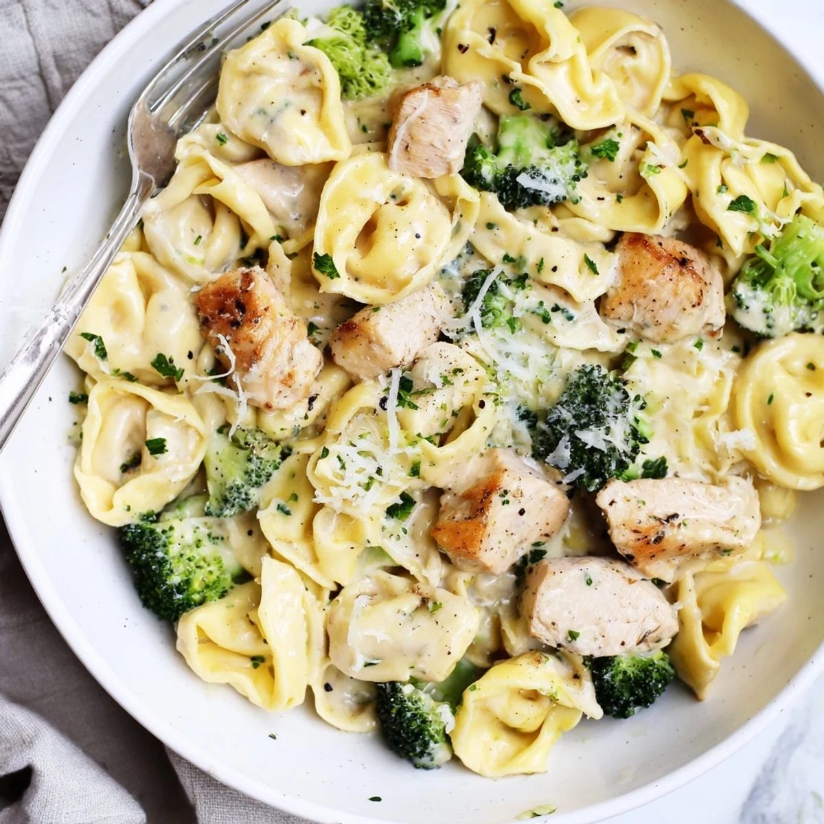 Steaming skillet of Creamy Garlic Parmesan Tortellini Chicken Broccoli Recipe with tender bites
