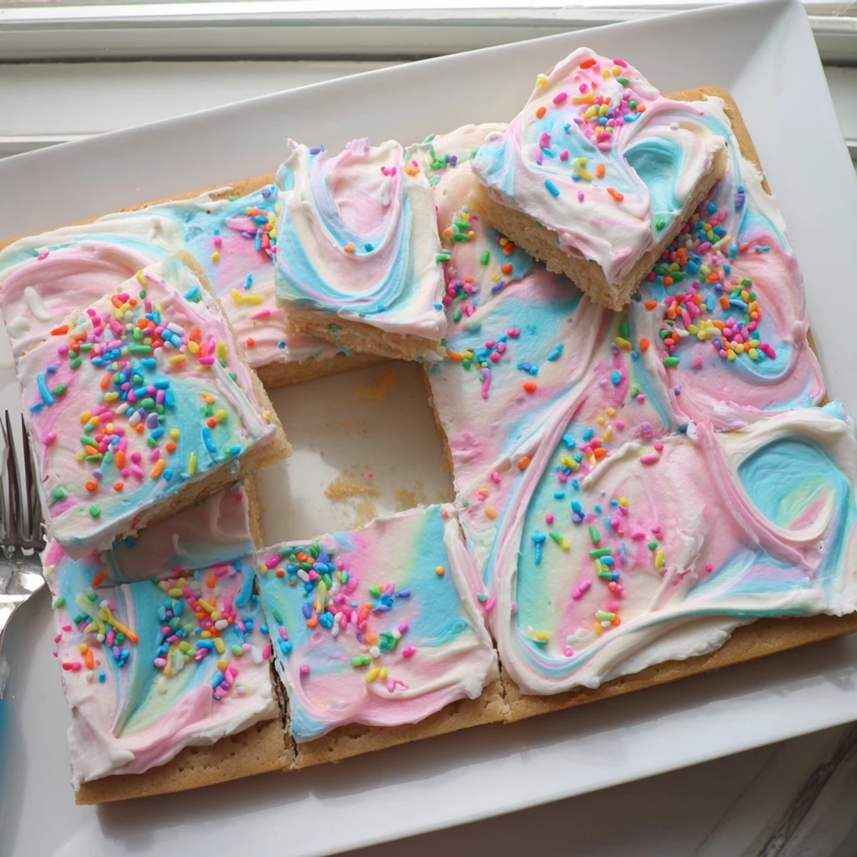 Golden frosted sugar cookie bars decorated with vibrant rainbow sprinkles for parties
