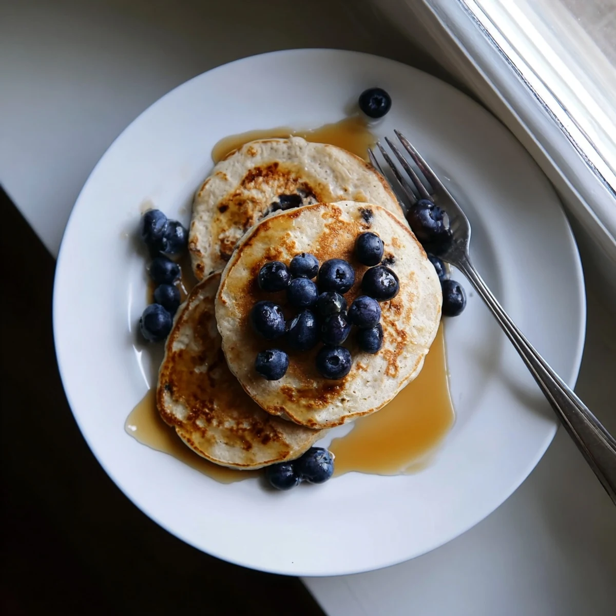 Thick fluffy protein banana pancakes stacked high with melted butter and a dusting of cinnamon
