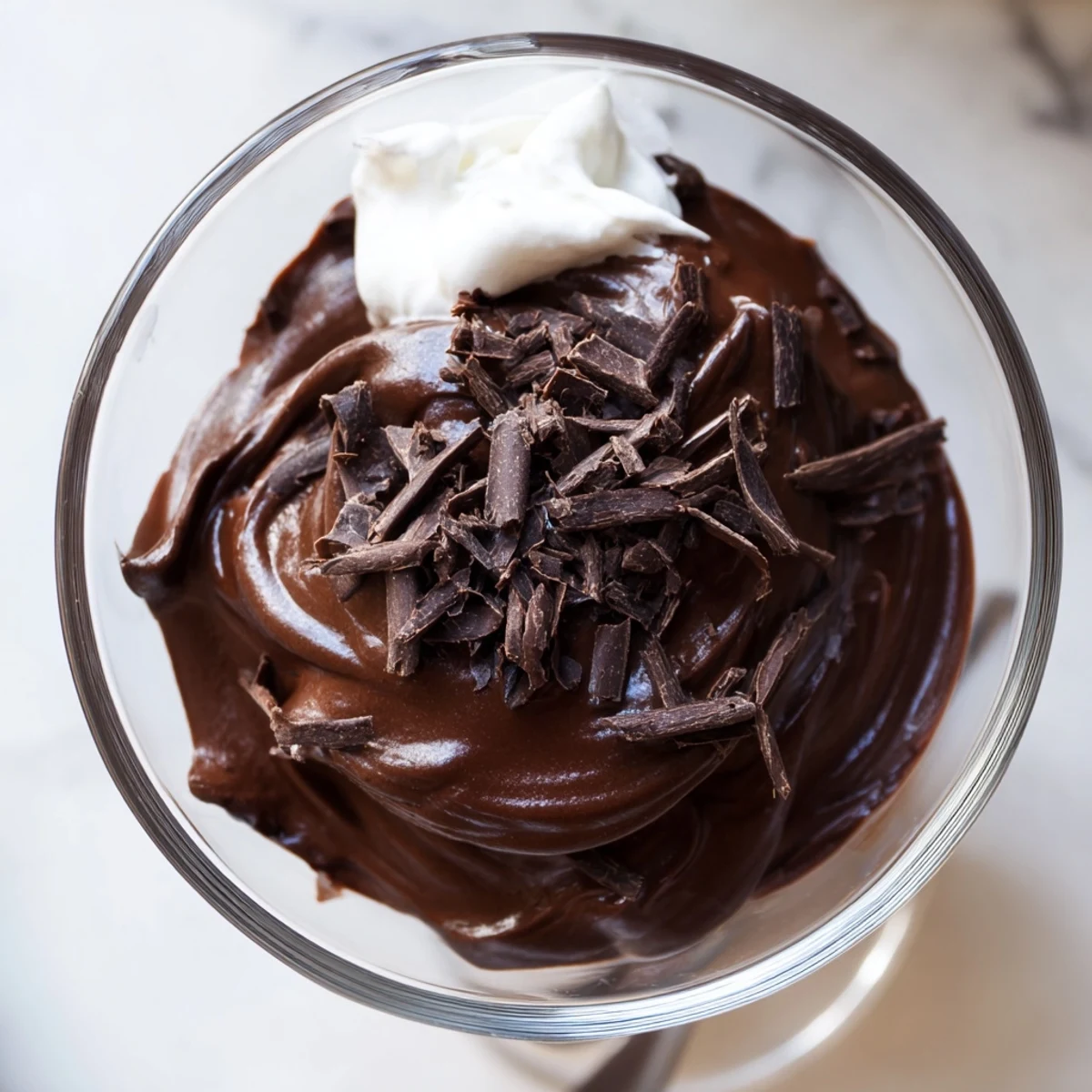 Creamy chocolate mousse scooped into ramekins with a dollop of whipped cream