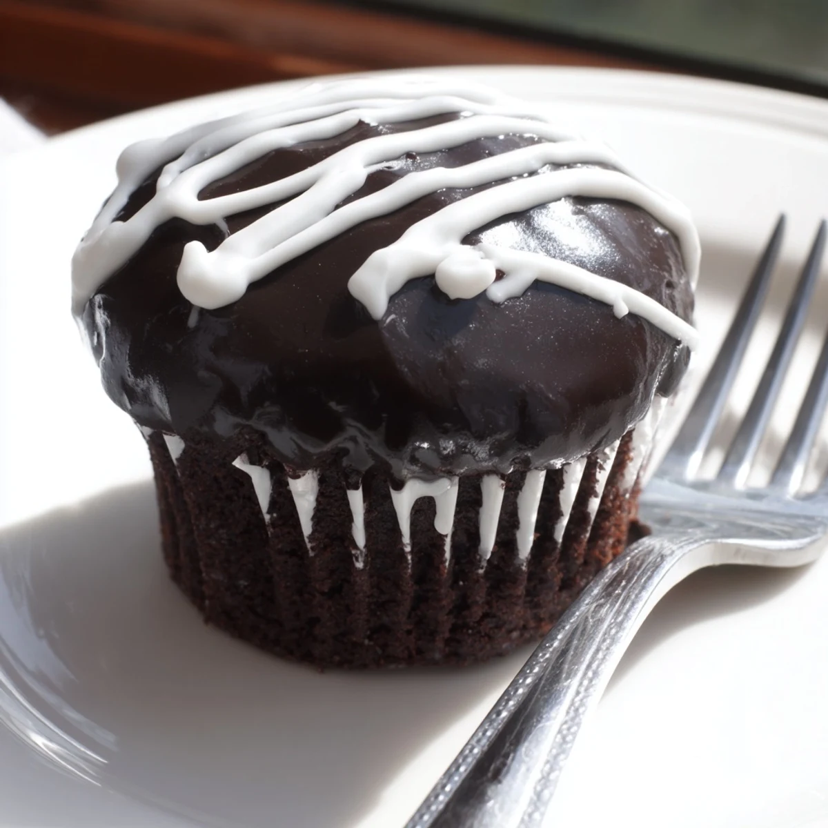 Decadent Homemade Hostess Cupcakes topped with shiny glaze and piped sugar swirl design