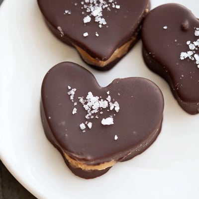 Freshly dipped chocolate peanut butter hearts with sea salt, arranged on parchment paper for easy serving.