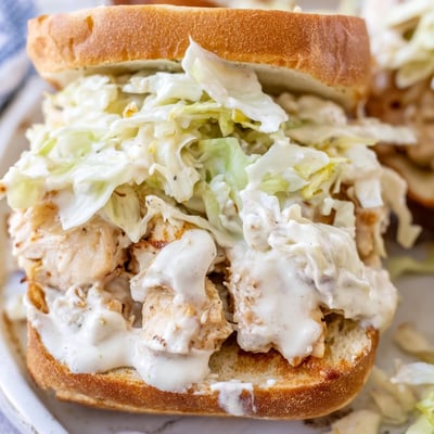 Tender smoked chopped chicken sandwich topped with crisp slaw and tangy white barbecue sauce