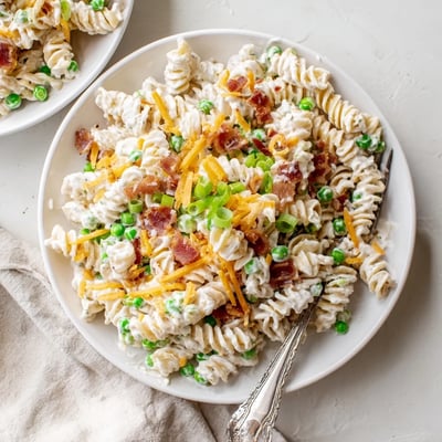Heaping bowl of ranch bacon pasta salad topped with green onions and shredded cheese