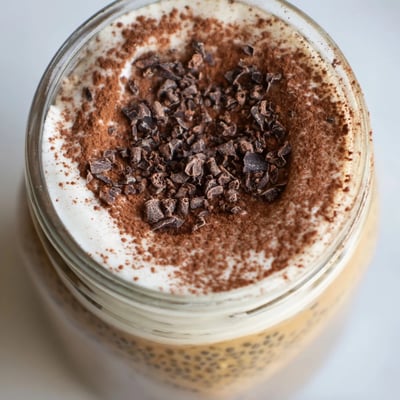 Tiramisu overnight oats served chilled in glass jars topped with a velvety mascarpone cream layer