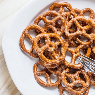 Golden brown butter toffee pretzels arranged on a white baking sheet with parchment paper.  
